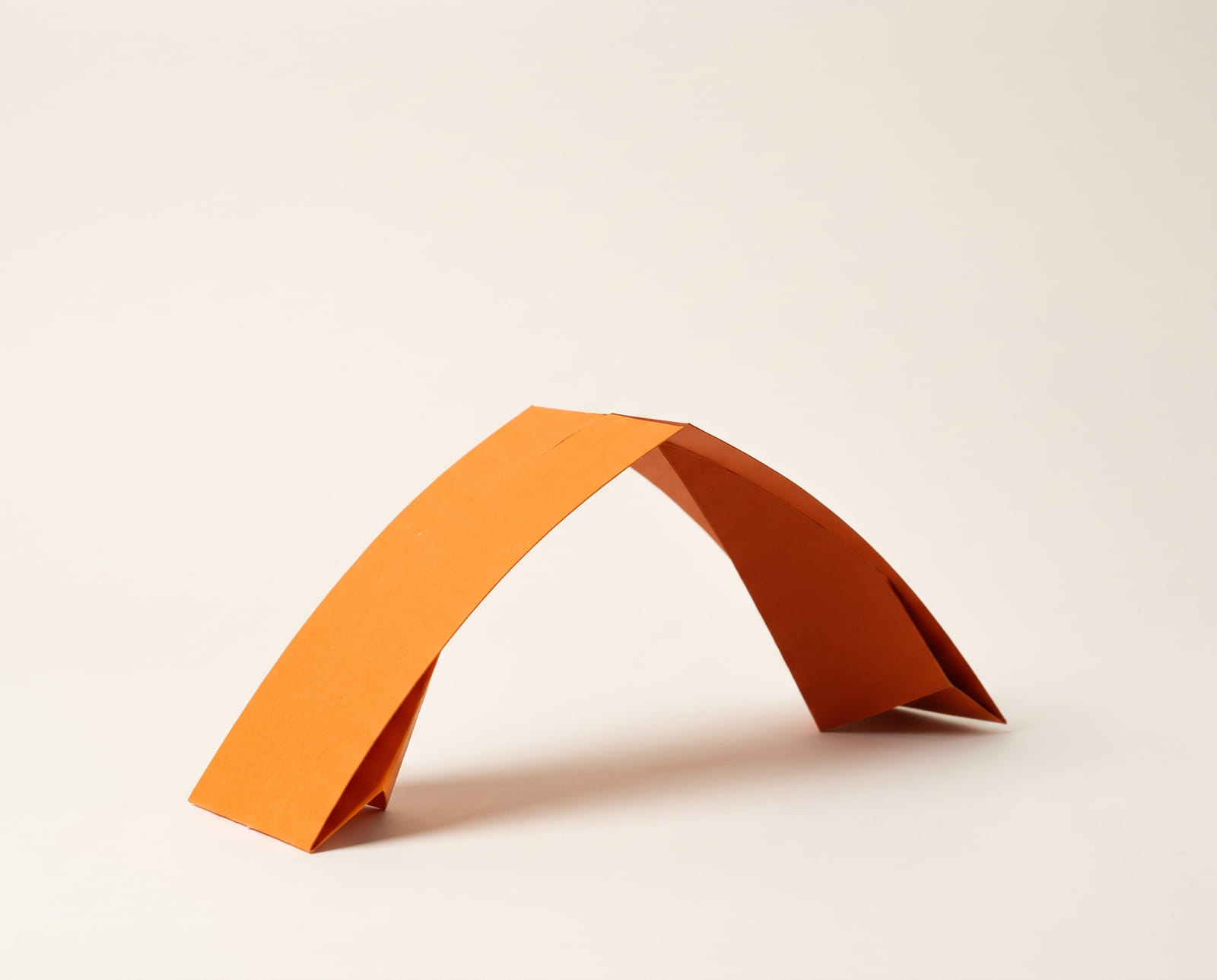 Twee oranje kartonnen stroken die van twee kanten komen en in het midden een brug vormen