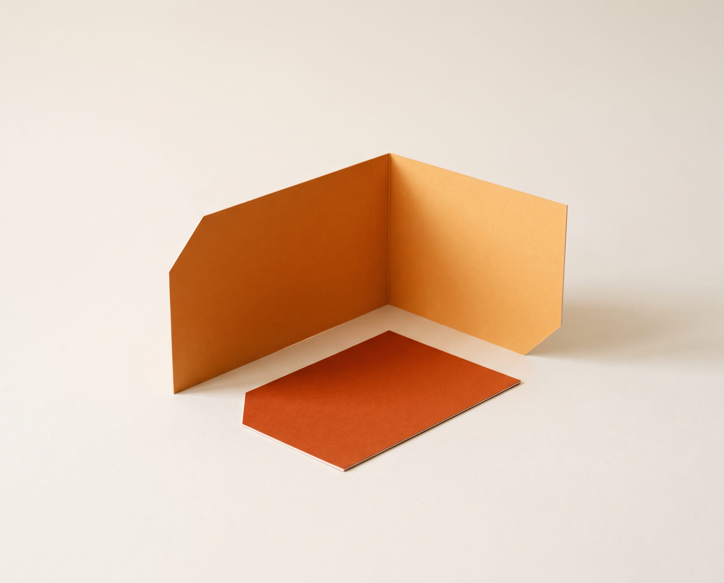 An orange card strip folded at a right angle as a standing corner, with a loose sheet in front